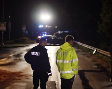 Zwei Polizisten nachts an einer Unfallstelle.