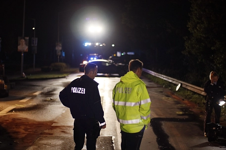 Zwei Polizisten nachts an einer Unfallstelle.
