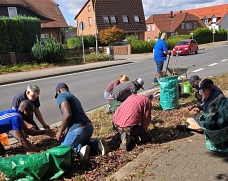WFUD/2. Termin B 188_3 Eine Gruppe von Menschen kniend und hockend bei der Gartenarbeit auf dem Grünstreifen an der B 188 in Osloß.